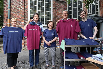 5 Menschen zeigen T-Shirts mit der Rücken-Aufschrift "Turmretter*in"
