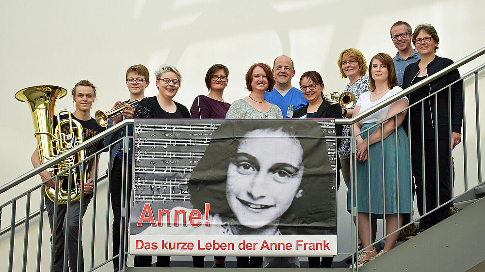 Ein kleiner Teil der Aufführenden: Mitwirkende des Projektchores der Krankenpflegeschule sowie Bläser des „b-teams“ freuen sich auf die Aufführung von „Anne! Damit wir klug werden“.