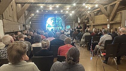 Besucher sitzen auf Stühlen im Alten Pastorat und hören einen Vortrag