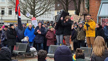 Viele Menschen bei Demo in Itzehoe. Darunter auch Propst Steffen Paar in einer gelben Jacke. Er spricht in ein Mikrophon. Junge Menschen neben ihm halten einen Verstärker in die Höhe.
