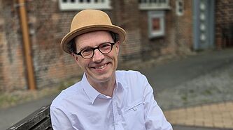 Musiker und Kulturreferent Frank Ramson sitzt vor der Nikolai-Kirche Elmshorn