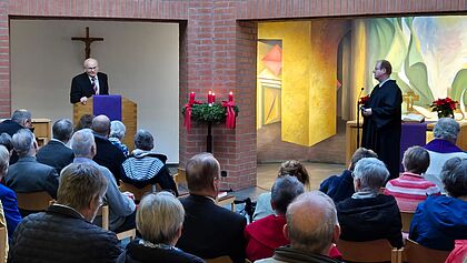 Voll besetzter Kirchraum mit predigendem Pastor 