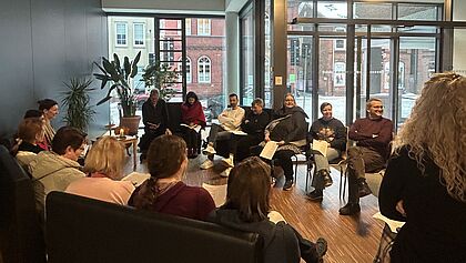 Eine Gruppe Menschen sitzt im Foyer.