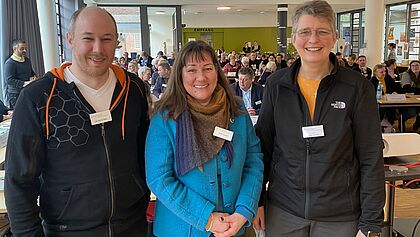 Ein Mann und zwei Frauen sind abgebildet; sie bilden das Synodenpräsidium