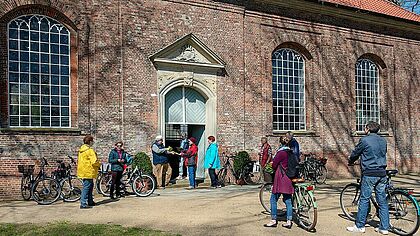 Radfahrer und Radfahrerinnen treffen sich vor der St. Jürgen Kirche in Horst