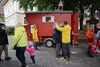 Propst Steffen Paar trägt eine gelbe Jacke. Er segnet ein Paar vor einer Schäferwagenkirche. 