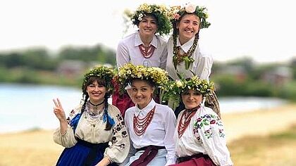 Fünf Frauen in ukrainischer Tracht sitzen auf Heuballen
