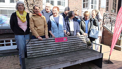 Eine Gruppe Frauen steht hinter einer Bank in der Fußgängerzone