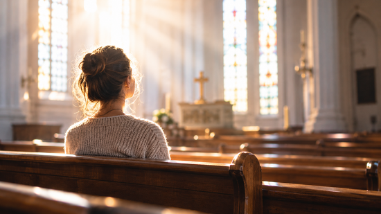 Frau sitzt in der lichtdurchfluteten Kirche 