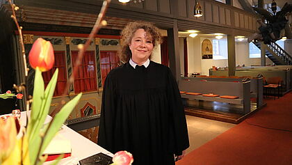 Pastorin Claudia Köckert im Talar in der Dorfkirche der Gemeinde Breitenberg