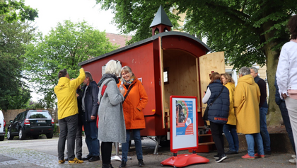 Menschen stehen an um in der roten Schäferwagenkirche Kerzen anzuzünden.