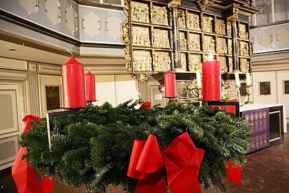 Adventskranz mit angezündeter Kerze in der St. Laurentii Kirche Itzehoe