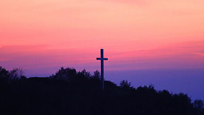 Kreuz auf einem Berg i Sonnenuntergang