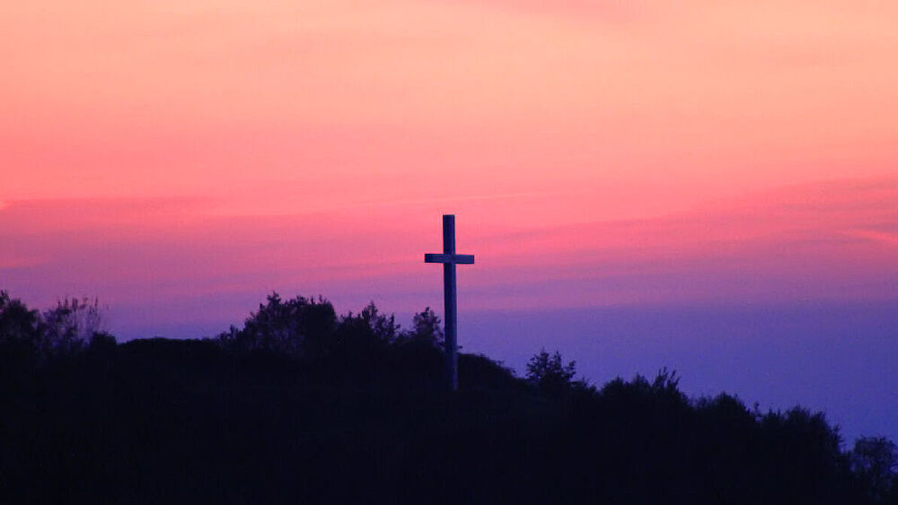 Kreuz auf einem Berg i Sonnenuntergang