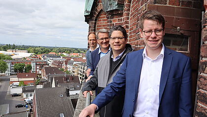 Vier Männer stehen auf dem schmalen Balkon des Kirchturms St. Nikolai. 