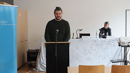 Tim Lukas Harken steht am Rednerpult vor der Synode