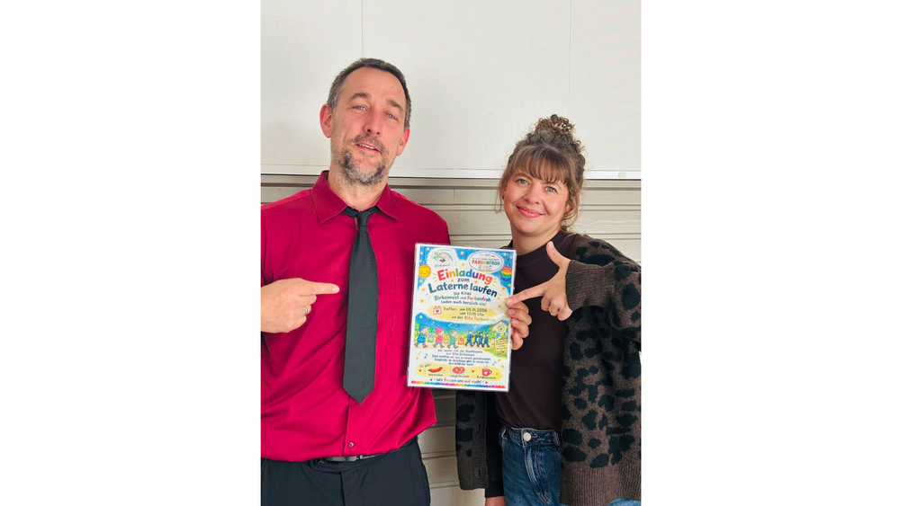 Nikolai Billerbeck und Martina Groß, die Kitaleitungen aus den evangelischen Kitas Birkennest und Farbenfroh in Krempe, halten ein Plakat in die Höhe, auf dem sie gemeinsam zum Laterne laufen einladen.