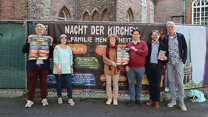 Sechs Personen posieren vor dem Banner der Lange Nacht der Kirchen
