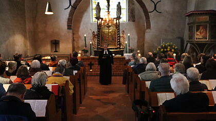 Pastorin steht vor dem neuen Altar in der voll besetzten Kirche
