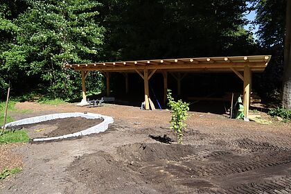 Bestattungswald mit Stein-Rondell für den neuen Altar. Im Hintergrund ist ein Holz-Unterstand zu sehen. 