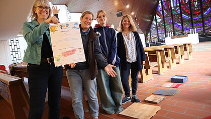 Vier Veranstalterinnen halten in der Kirche das Plakat hoch.