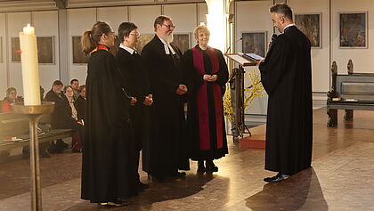Propst Steffen Paar mit Pastor Lothar Volkelt und anderen Personen, alle im Talar, im Altarraum der Kirche.