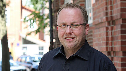 Timo Milewski, Gemeindemanager für die Region Wilster und Wilstermarsch vor der Kirche in Wilster