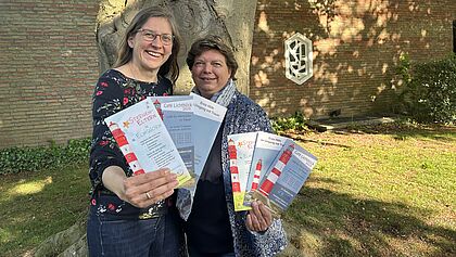 Pastorin und Trauerbegleiterin zeigen ihre Flyer