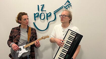 Anne Petersen hält eine E-Gitarre in der Hand und Stephan Reinke ein E-Piano